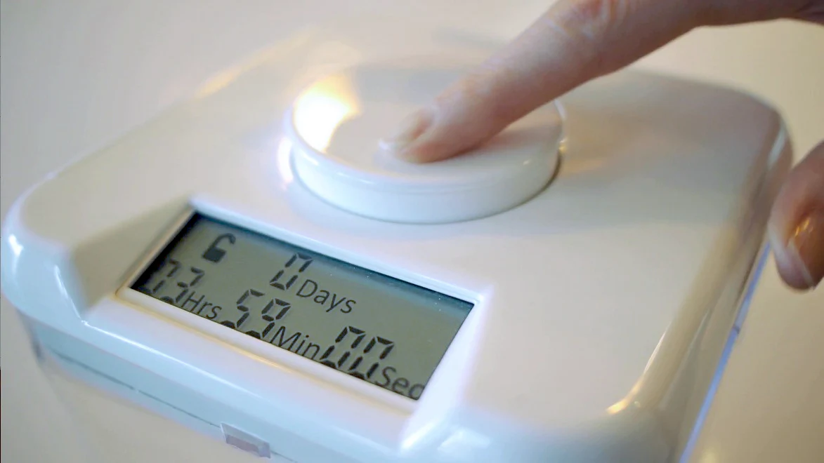 A person's hand is turning the dial on the KSafe, setting the timer to lock away their phone for a deep focus session.