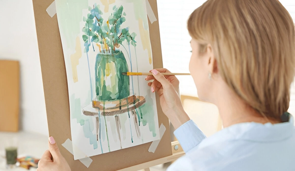 A woman rediscovering her creativity by painting, a benefit of taking scheduled breaks from her smartphone.